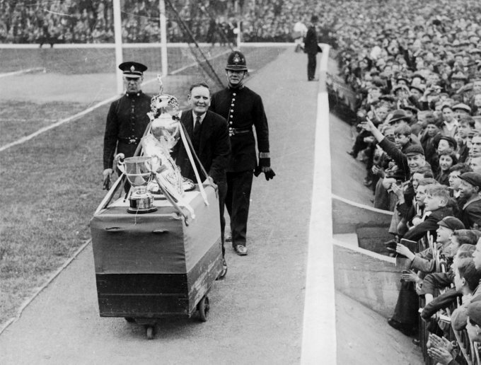 Os trof&eacute;us do Arsenal sendo exibidos para a torcida em 1934. Repare como os torcedores se amontoavam &agrave; beira do gramado