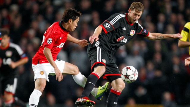 Manchester United's Shinji Kagawa, left, and Bayer Leverkusen's Stefan Kiessling battle for the ball during their Champions League Group A soccer match at Old Trafford in Manchester, England, Tuesday Sept 17, 2013. (AP Photo/Jon Super)