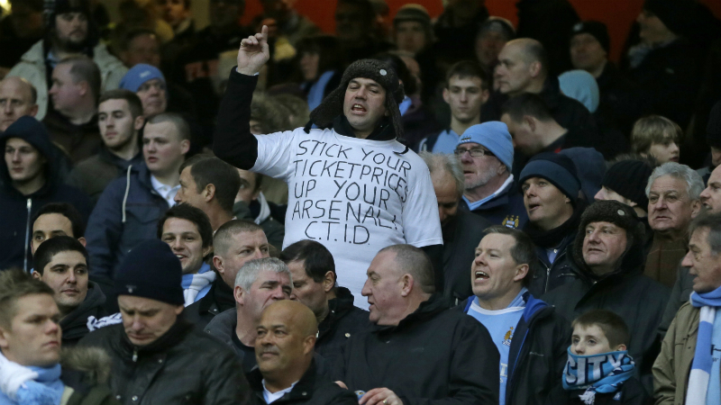 "Enfie o pre&ccedil;o do ingresso no seu 'Arsenal'", protesta torcedor do City no Emirates, em 2013 (AP Photo/Alastair Grant)