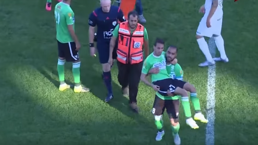 Depois de cair da maca, jogador tem que ser carregado pelo capit&atilde;o do time para fora de campo