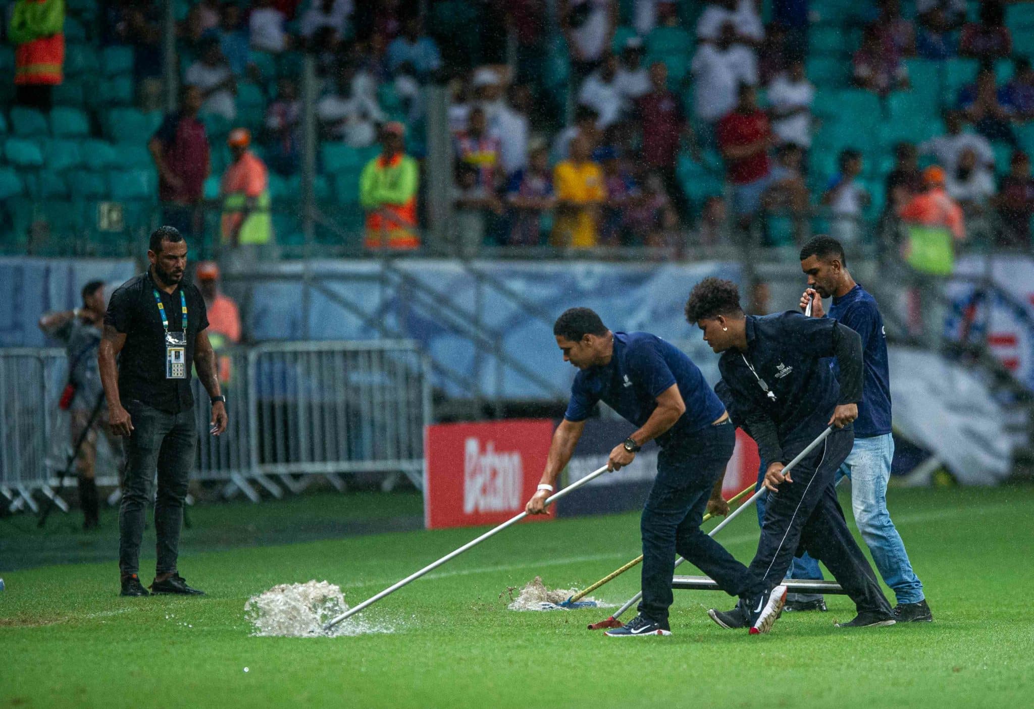 Funcion&aacute;rios do Bahia usaram rodos para ajudar a secar o gramado afetado pelas chuvas - Foto: Icon sport