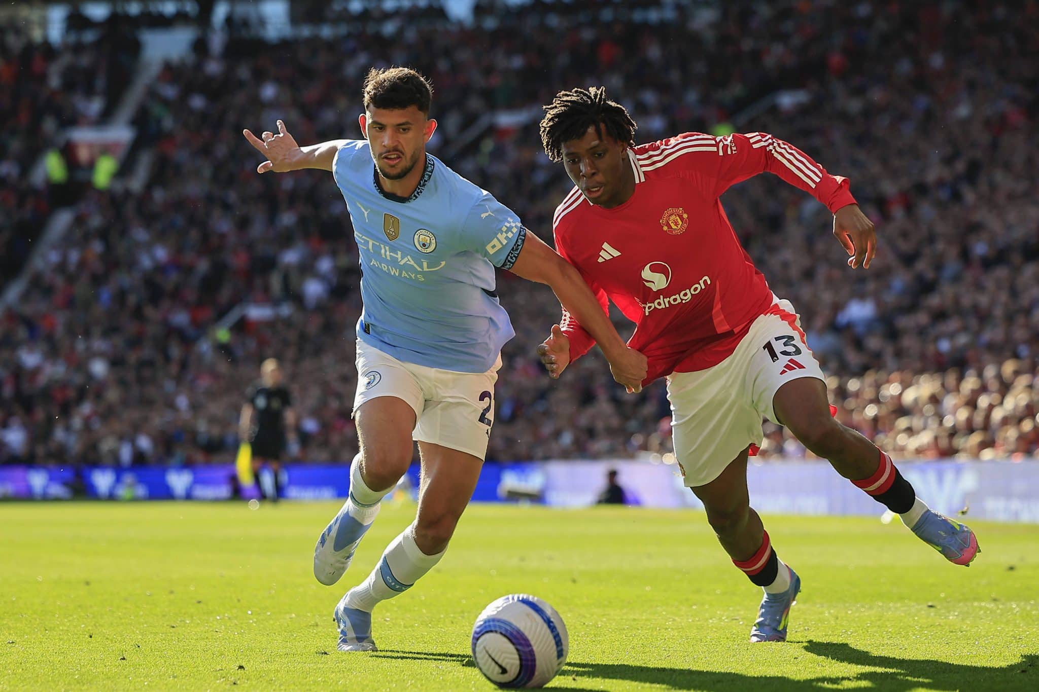 Patrick Dorgu em disputa de bola com Matheus Nunes em United x City